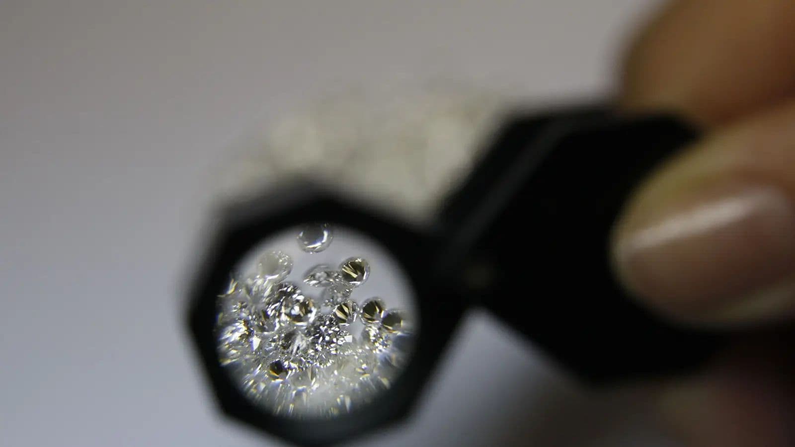 A jeweller examining loose gemstones through a loupe