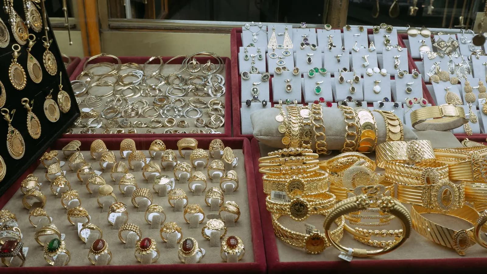 Jewellery display case with trays of gold rings, bangles, pendants and gemstone earrings