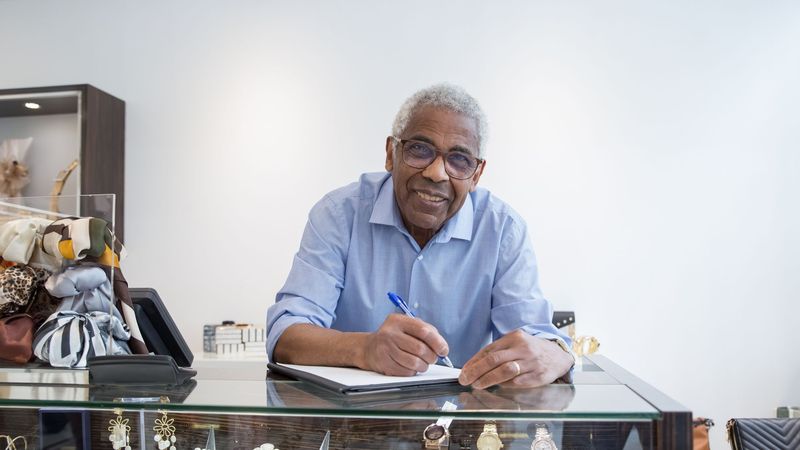 A jewellery store manager writing at the counter behind the display case